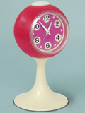 in purple and white plastic is a Goldbühl wind-up alarm clock on a pedastal base (c.1967, West Germany). It's about four inches across. From 'A Collection of Clocks' at the web's largest private collection of antiques & collectibles: https://www.ericwrobbel.com/collections